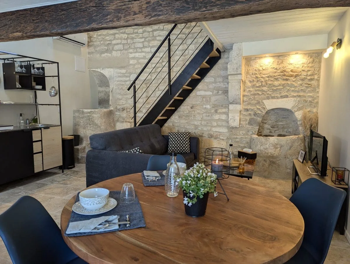 Charmant salon aux allures de maison d'hôtes à Angoulême : pierres de Charente, table rustique, cuisine équipée, ambiance chaleureuse.
