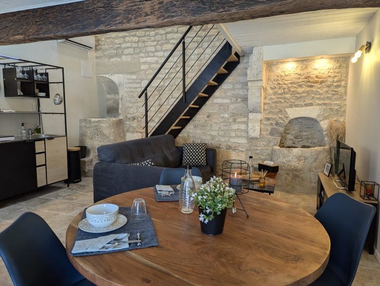 Charmant salon aux allures de maison d'hôtes à Angoulême : pierres de Charente, table rustique, cuisine équipée, ambiance chaleureuse.