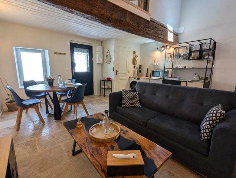 Un espace convivial dans le style d'une maison d'hôtes en Charente, un salon chaleureux, une table en bois, une cuisine équipée à Angoulême, un sol en pierre.