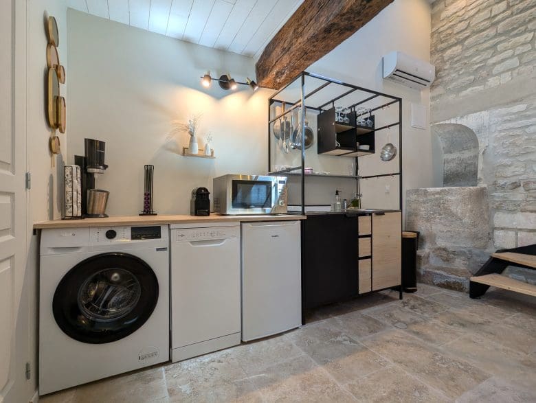 Cuisine et buanderie de charme dans le style charentais, avec pierres et poutres apparentes, équipées de manière moderne, près d’Angoulême.