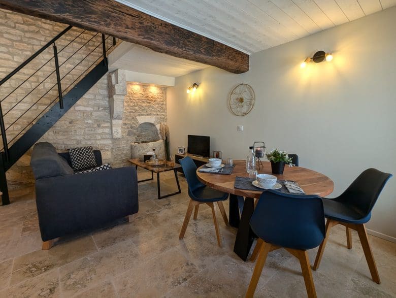 Un salon-séjour chaleureux aux murs en pierre, à la décoration charentaise et doté d’une table en bois, situé à deux pas d’Angoulême, dans une ambiance de maison d’hôtes.