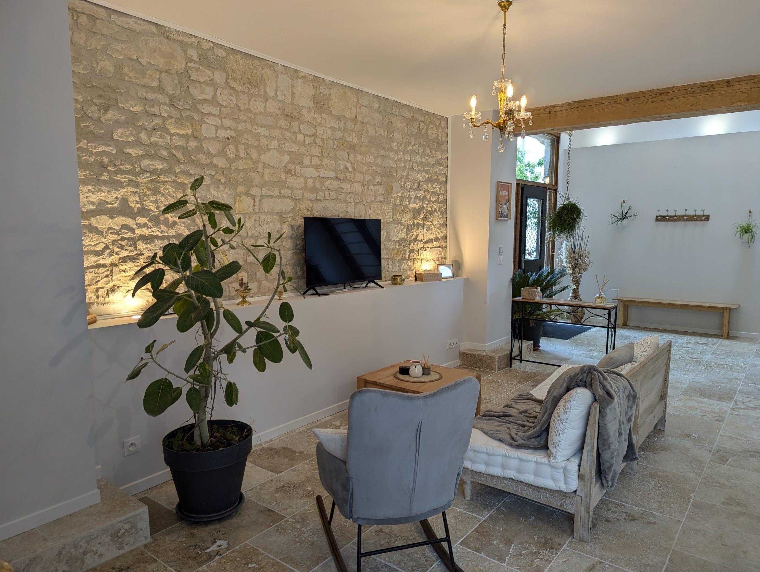 Un charmant salon aux allures de maison d’hôtes à Angoulême, avec ses murs en pierre de Charente, sa décoration chaleureuse et sa lumière douce et accueillante.