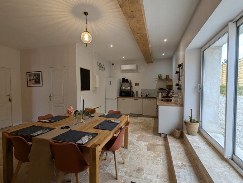 Salle à manger conviviale, dans le style d’une maison d’hôtes près d’Angoulême, avec une table en bois, des poutres charentaises et une lumière naturelle chaleureuse.
