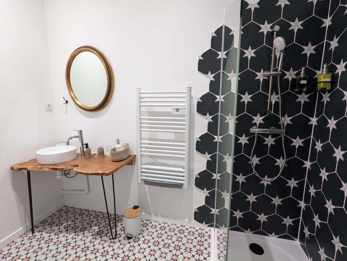 Salle de bain moderne dans le style d’une maison d’hôtes à Angoulême, en Charente : meuble en bois, sol plein de charme, douche étoilée, ambiance chaleureuse.