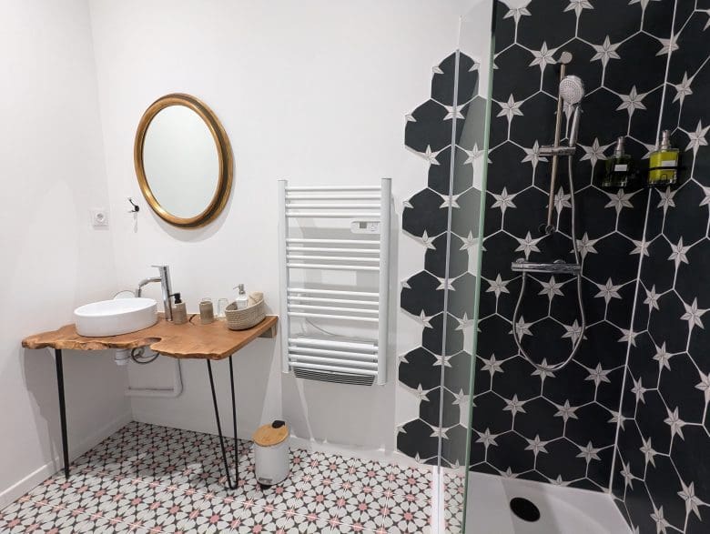 Salle de bain moderne dans le style d’une maison d’hôtes à Angoulême, en Charente : meuble en bois, sol plein de charme, douche étoilée, ambiance chaleureuse.