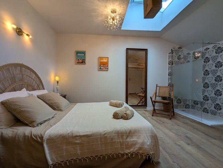 Chambre douillette à Angoulême, lit double, décoration typique de la Charente, parquet, fauteuil en osier, douche vitrée carrelée et lucarne.