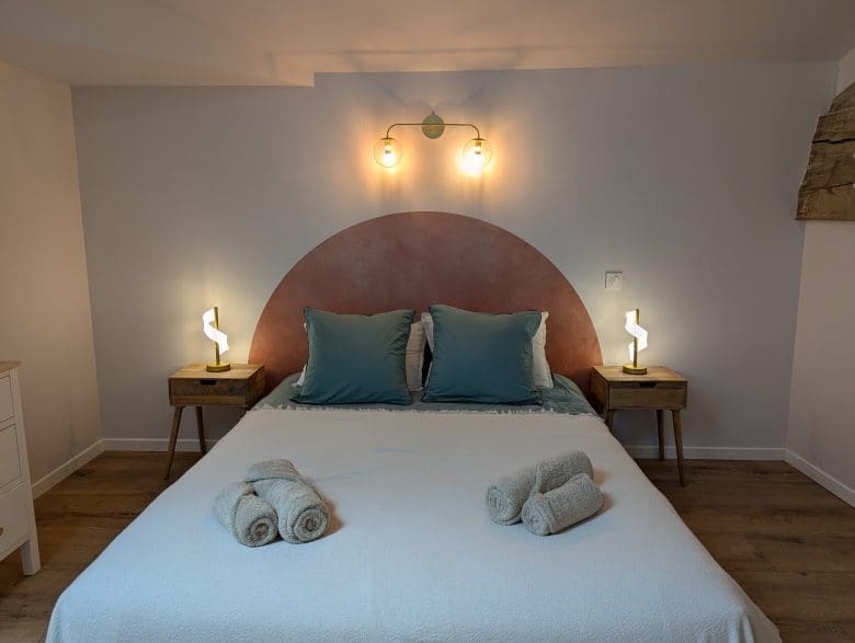 Un lit soigneusement préparé, des coussins bleus et des serviettes enroulées : l'ambiance chaleureuse d'une maison d'hôtes à Angoulême, en Charente.