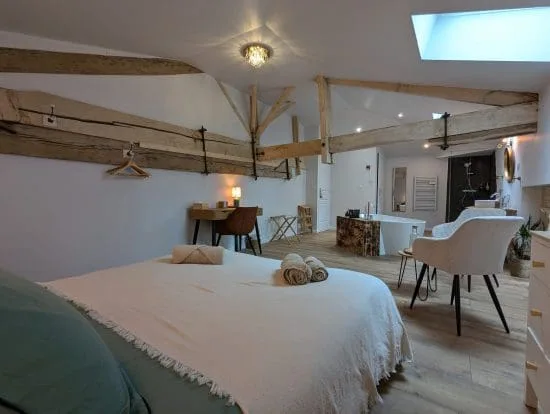 Chambre d'hôtes chaleureuse à Angoulême, avec poutres apparentes de style charentais, lit double, bureau, salle de bains moderne et ambiance accueillante.
