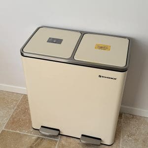 Jolie poubelle crème à deux compartiments posée sur du carrelage, avec étiquettes de tri, à Les Pierres Douces près d’Angoulême, en Charente.